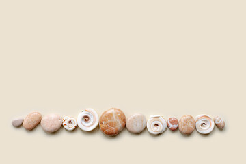 Top view close up colored pebbles sea stones and shells on sand color background. Row from natural round smooth stone neutral tones. Minimal style banner, summer concept, empty space