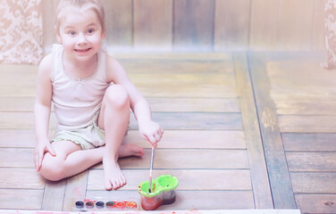 Little children paint on a large sheet of paper