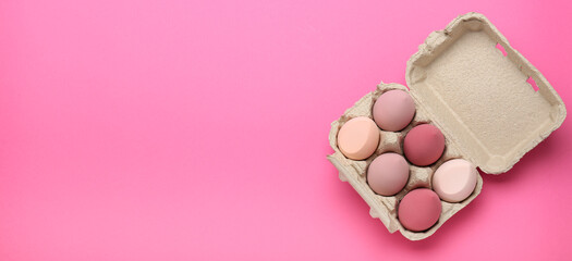 make-up sponges in an egg box on pink background. beauty concept, top view