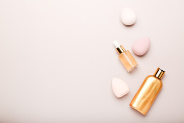 makeup sponges and cosmetics on a beige background. Beauty concept, top view, space for text