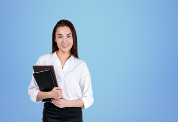 Fototapeta premium Young businesswoman with notebook, smiling on blue background