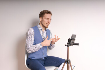 Young business man in shirt gesticulates while creating video in social networks online broadcast...