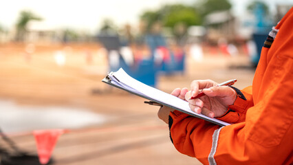 Action of safety officer is writing and check on checklist document during safety audit and...
