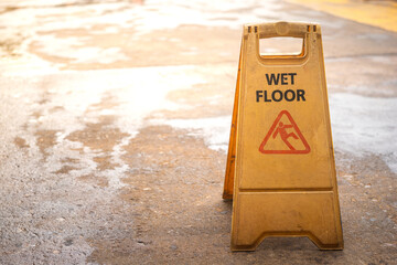 "Wet floor" with slip icon, caution safety sign which is placed in front of the wet ground area. Close-up and selective focus.