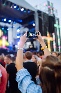 Using a smartphone in a public event, live music festival. Holding a mobile phone in hands and shooting photo or video content. Youth, party, vacation concept.