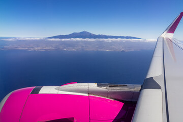 Window view from an airplane on the volcano mountain peak of Pico del Teide on Tenerife, Canary Islands, Spain, Europe, EU. High peak are shrouded in clouds. Flying high above the ground. Freedom