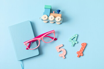 Child eyeglasses over blue pastel background. Optical store, glasses selection for kids, eye test, vision examination at optician concept. Top view, flat lay