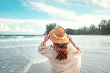 Summer beach vacation concept, Young woman with hat relaxing with her arms raised to her head...