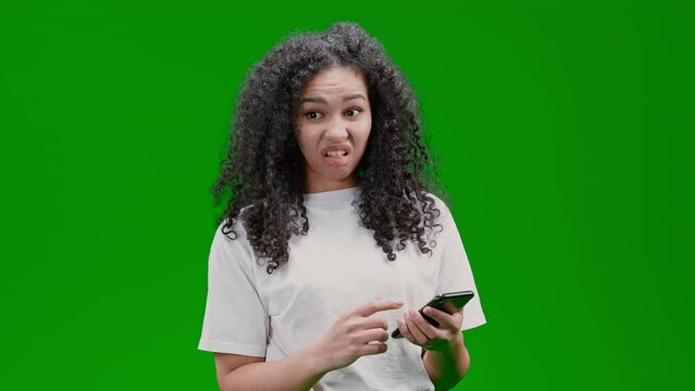 shocked woman with curly long hair dressed white shirt holding smartphone reading message or watching something disgusting Isolated on Green Screen