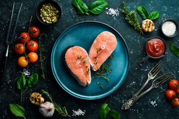 Fish. Raw fresh salmon or trout steaks on a plate. Top view. On a black stone background.