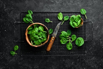 Fresh green spinach in a bowl. On a black stone background. Top view.