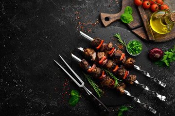 Traditional Kebab. Juicy pork skewers with vegetables on a black stone plate. Barbecue. Top view....