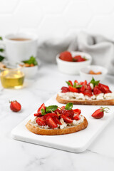 Sweet strawberry dessert. Toast with strawberry, cottage cheese, ricotta cheese, honey, almond and mint. Sandwich, Bruschetta, snack, appetizers with strawberry.