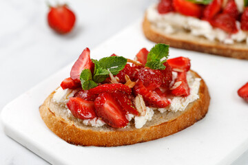 Fototapeta na wymiar Toast with strawberry, cottage cheese, ricotta cheese, honey, almond and mint. Sweet strawberry dessert. Sandwich, Bruschetta, snack, appetizers with strawberry.