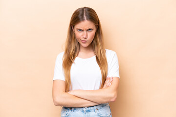 Young caucasian woman isolated on beige background with unhappy expression