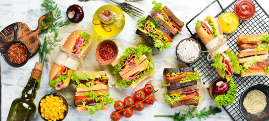 Sandwiches and burgers on a white wooden background. Top view. Street food.