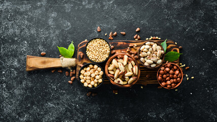 Assortment of nuts: pistachios, hazelnuts, pine nuts on a black stone background. free space for your text. Top view.