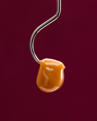 Live rosin dangling on the end of a hook with a red background.  - obrazy, fototapety, plakaty