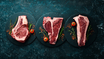 Meat. Set of raw steaks - t-bone, tomahawk, striploin, tenderloin, new york steak. Flat lay top view on black stone cutting table.