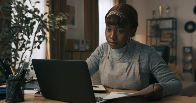 A young girl takes a break from work to write back overdue messages. The woman tries to use the time spent at desk productively and writes everything down so as not to forget anything.