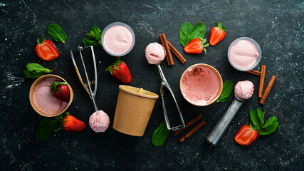 Fototapeta na wymiar Strawberry ice cream with mint and strawberries. Ice cream spoon. On a black stone background, top view.
