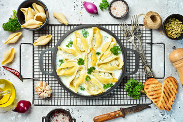 Pasta stuffed with meat, cream sauce and parmesan. In a frying pan. Traditional Italian lunch. On a stone background. Recipe.