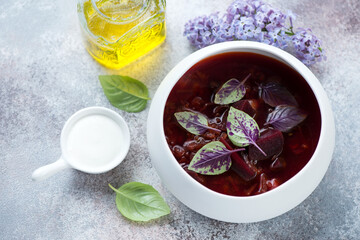 Red beetroot soup or borsch served in a white bowl, high angle view on a roseate stone background, studio shot