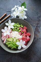 Hawaiian tuna poke bowl on a dark-grey cracked asphalt background, elevated view, vertical shot