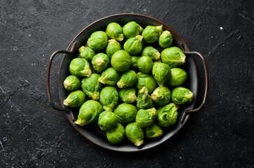 Fresh brussels sprouts in a metal tray on a black stone background. Healthy food. Top view.