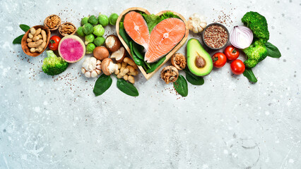 Fototapeta na wymiar The concept of healthy food: nuts, salmon, avocados, spinach, mushrooms, berries. On a stone background. Top view. Copy space.