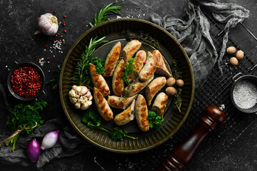 Grilled sausages with rosemary and spices. Barbecue. On a black stone background.