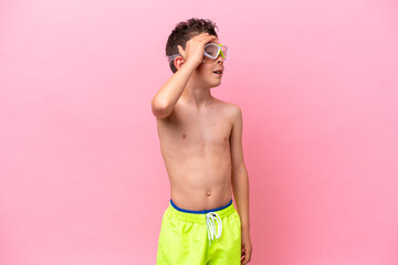 Fototapeta premium Little caucasian boy wearing a diving goggles isolated on pink background smiling a lot