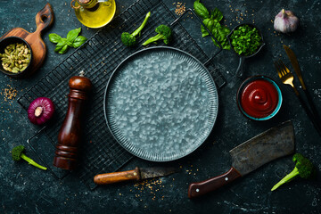 Cooking background: metal plate, vegetables and spices. Top view. On a stone background.