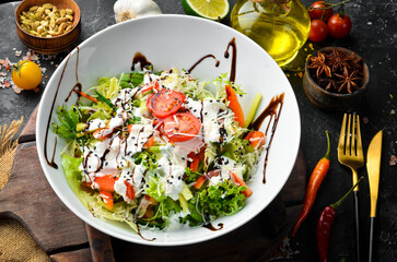 Vegetable salad: lettuce, tomatoes, cucumber and cream sauce. Caesar. Top view. Top view. Rustic style.