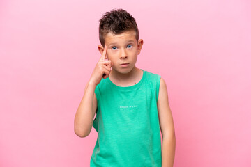 Little caucasian boy isolated on pink background thinking an idea