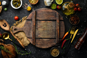 Wooden board on a black stone table with vegetables and spices. Food background. Top view. Rustic style.