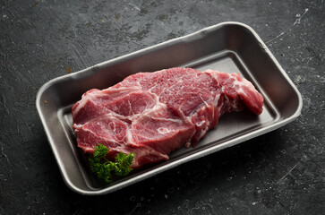 Pork. Piece of raw fresh pork steak on black slate stone background. Top view. Cooking.