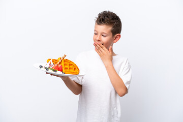 Little caucasian boy holding a waffles isolated on white background with surprise and shocked facial expression