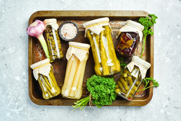 Assortment of pickled vegetables in a glass jar. Food supplies. On a stone background. Top view.