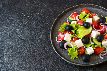 Greek salad on a round dish. Dark background.