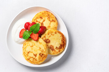 Cottage cheese pancakes with sour cream and berries on a gray background. Cheesecakes, top view