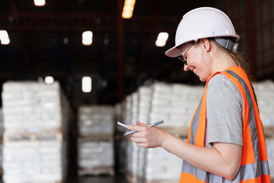 Female worker using digital tablet checking cargo shipment at courier distribution shipping dock