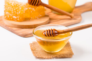 Honey dripping from a wooden honey dipper on white background. Healthy organic food concept. 