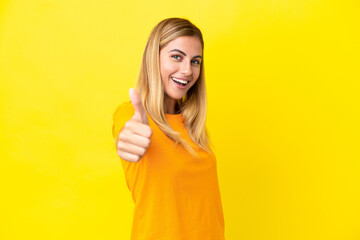 Obraz premium Blonde Uruguayan girl isolated on yellow background with thumbs up because something good has happened