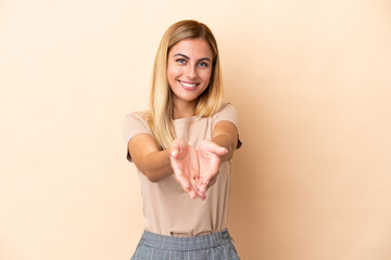 Obraz premium Blonde Uruguayan girl isolated on beige background holding copyspace imaginary on the palm to insert an ad