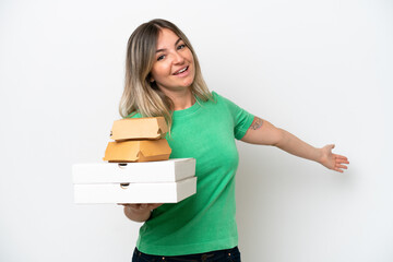 Fototapeta premium Young Rumanian woman holding fast-food isolated on white background extending hands to the side for inviting to come