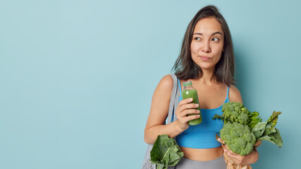 Healthy detox concept. Thoughtful Asian woman holds bottle of fresh smoothie for weight loss made...
