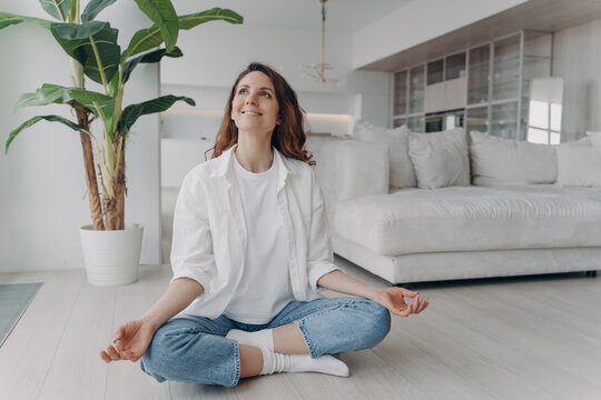 Peace of mind and mental health concept. Young european woman practicing yoga on floor and smiling. - Powered by Adobe