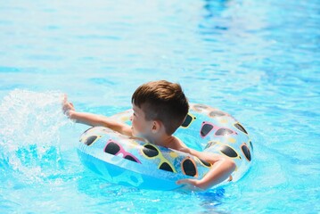 Happy Young Boy Floating in Swimming Pool on Raft