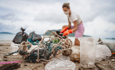 Obraz premium A female ecologist volunteer cleans the beach on the seashore from plastic and other waste